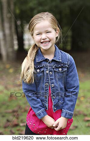 Stock Image - Smiling girl standing in rural field. Fotosearch