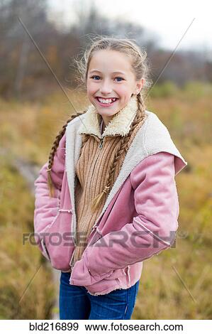 Stock Photo - Smiling girl standing with hands in pockets in field. Fotosearch