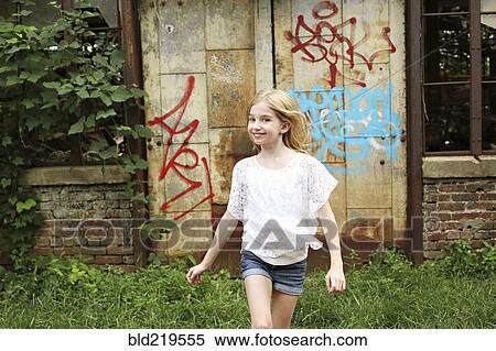 Smiling girl walking outside dilapidated building View Large Photo Image Stock Photography - Smiling girl walking outside dilapidated building. Fotosearch