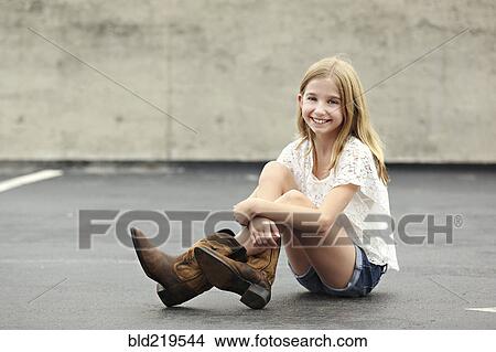 Picture - Smiling girl wearing cowboy boots in parking lot. Fotosearch