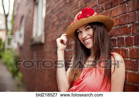 Stock Photo - Smiling girl wearing straw hat near brick wall. Fotosearch