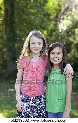 Stock Image - Smiling girls hugging in backyard. Fotosearch