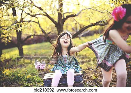 Stock Image - Smiling girls playing in orchard. Fotosearch