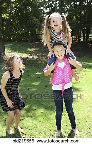 Stock Photograph - Smiling girls playing in rural field. Fotosearch