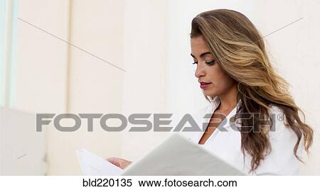 Smiling Hispanic doctor reading folder View Large Photo Image Stock Photography - Smiling Hispanic doctor reading folder. Fotosearch