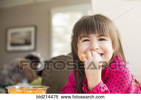 Stock Photography - Smiling Hispanic girl eating fruit. Fotosearch