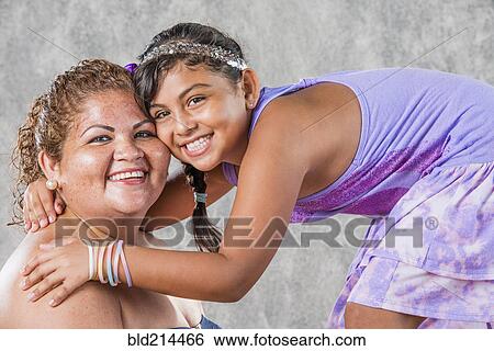 Stock Photograph - Smiling Hispanic mother and daughter hugging. Fotosearch