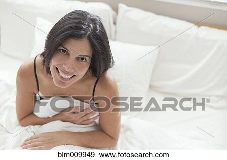 Stock Photo - Smiling Hispanic sitting in bed. Fotosearch