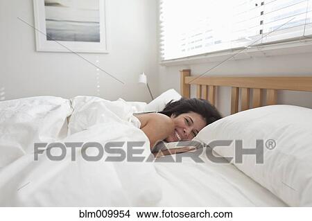 Smiling Hispanic woman laying in bed View Large Photo Image Picture - Smiling Hispanic woman laying in bed. Fotosearch