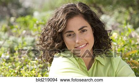 Picture - Smiling Hispanic woman sitting in garden. Fotosearch