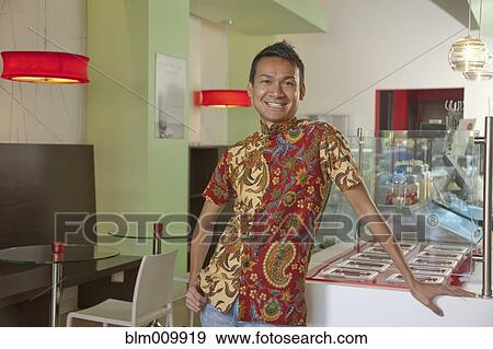 Stock Photo - Smiling Malaysian man standing in cafe. Fotosearch