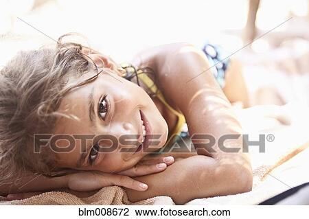 Stock Image - Smiling mixed race girl sunbathing. Fotosearch