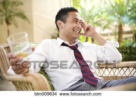 Smiling mixed race man drinking on patio View Large Photo Image Picture - Smiling mixed race man drinking on patio. Fotosearch