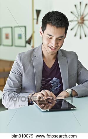Stock Photo - Smiling mixed race man in jacket using digital tablet. Fotosearch