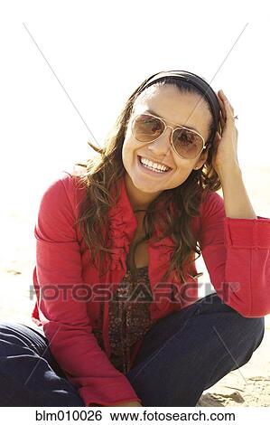 Smiling mixed race woman sitting on beach View Large Photo Image Stock Photograph - Smiling mixed race woman sitting on beach. Fotosearch