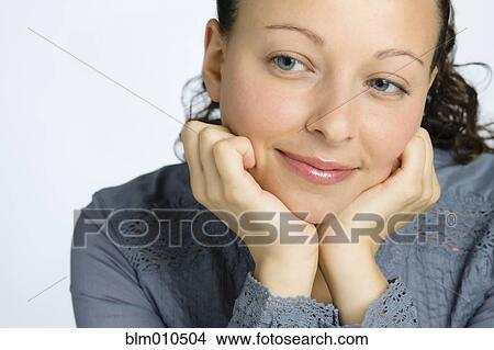 Picture - Smiling mixed race woman with head in hands. Fotosearch
