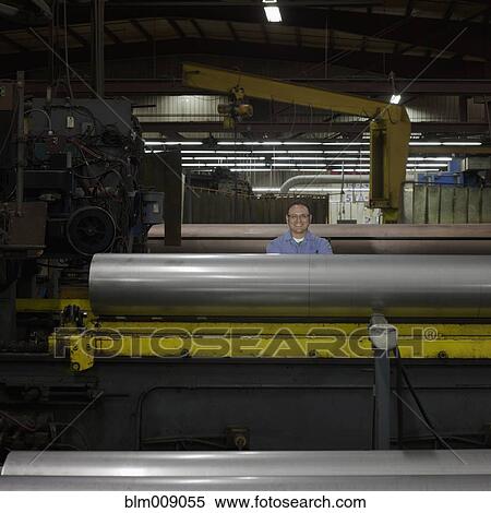Stock Photography - Smiling mixed race worker standing in factory. Fotosearch