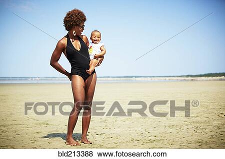 Smiling mother holding girl on beach View Large Photo Image Stock Photo - Smiling mother holding girl on beach. Fotosearch