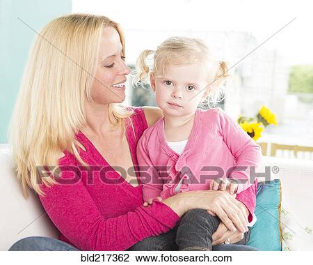 Smiling mother hugging serious daughter View Large Photo Image Stock Image - Smiling mother hugging serious daughter. Fotosearch