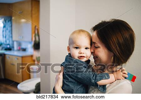Picture - Smiling mother nuzzling son in kitchen. Fotosearch
