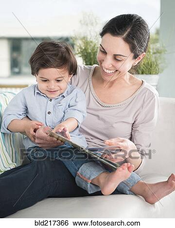 Smiling mother reading to son on sofa View Large Photo Image Stock Photograph - Smiling mother reading to son on sofa. Fotosearch