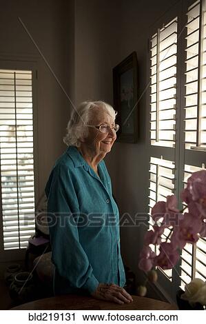 Smiling older Caucasian woman looking out window View Large Photo Image Stock Image - Smiling older Caucasian woman looking out window. Fotosearch