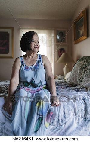 Smiling older woman sitting on bed View Large Photo Image Stock Image - Smiling older woman sitting on bed. Fotosearch