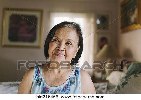 Stock Photograph - Smiling older woman sitting on bed. Fotosearch