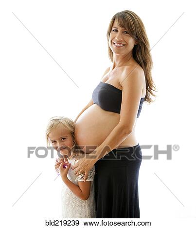 Stock Photo - Smiling pregnant Caucasian mother hugging daughter. Fotosearch