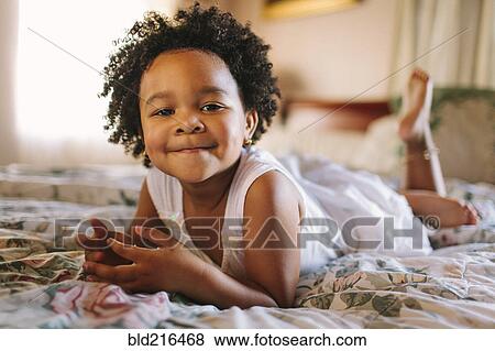 Smiling toddler girl playing on bed View Large Photo Image Stock Photo - Smiling toddler girl playing on bed. Fotosearch