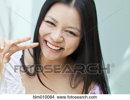 Smiling Vietnamese woman making peace sign gesture View Large Photo Image Picture - Smiling Vietnamese woman making peace sign gesture. Fotosearch
