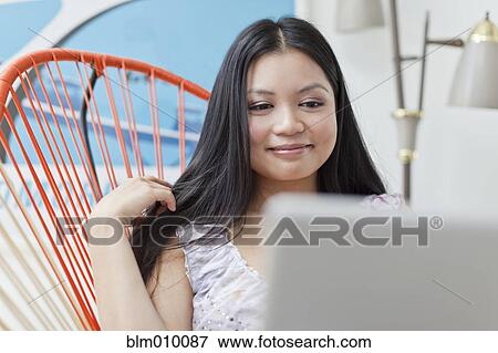 Smiling Vietnamese woman using laptop View Large Photo Image Stock Photo - Smiling Vietnamese woman using laptop. Fotosearch