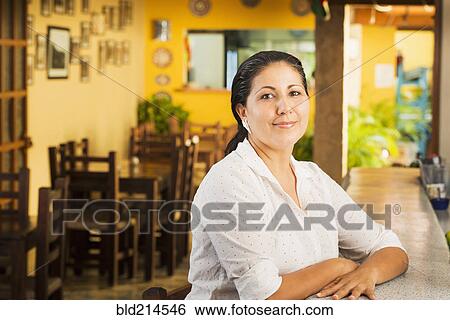 Stock Photograph - Smiling woman at counter in restaurant. Fotosearch