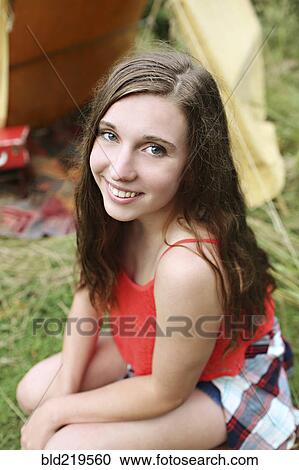 Stock Image - Smiling woman crouching at camping tent. Fotosearch