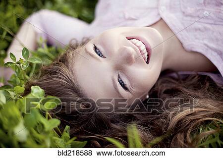 Stock Photo - Smiling woman laying in grass. Fotosearch