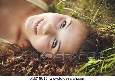 Stock Photography - Smiling woman laying in grass. Fotosearch