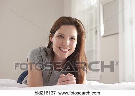 Stock Photo - Smiling woman laying on bed. Fotosearch