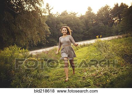 Stock Photo - Smiling woman running in rural field. Fotosearch