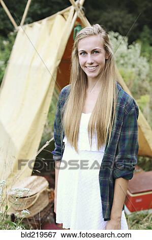 Stock Photo - Smiling woman standing at camping tent. Fotosearch