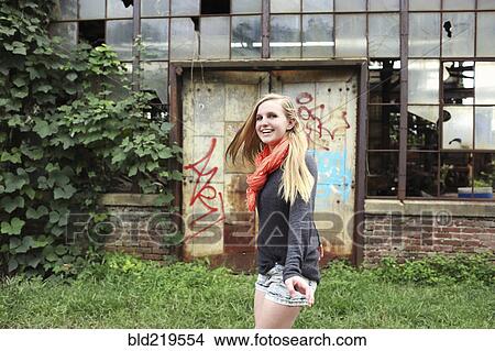 Smiling woman walking outside dilapidated building View Large Photo Image Picture - Smiling woman walking outside dilapidated building. Fotosearch
