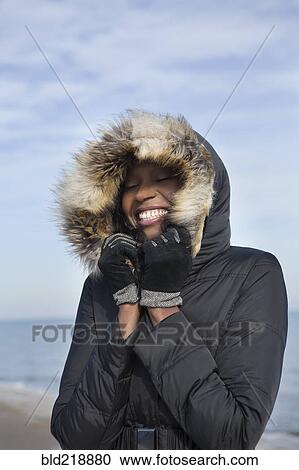 Smiling woman wearing coat on beach View Large Photo Image Stock Image - Smiling woman wearing coat on beach. Fotosearch