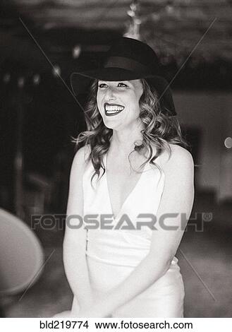 Picture - Smiling woman wearing sun hat in backyard. Fotosearch