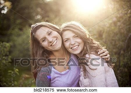 Stock Photography - Smiling women hugging in rural field. Fotosearch