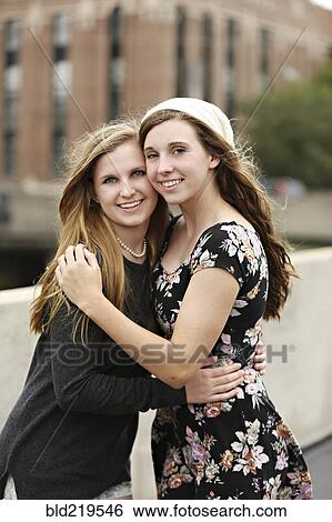 Stock Photograph - Smiling women hugging on urban rooftop. Fotosearch