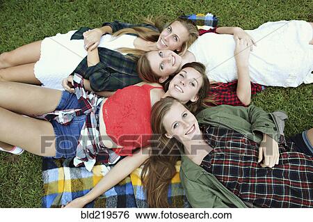 Smiling women laying on blanket in grass View Large Photo Image Stock Photograph - Smiling women laying on blanket in grass. Fotosearch