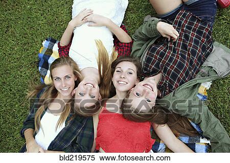 Stock Photography - Smiling women laying on blanket in grass. Fotosearch