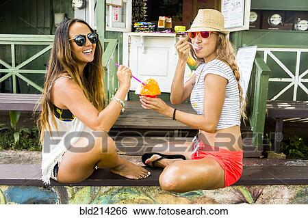 Stock Photograph - Smiling women sharing shaved ice. Fotosearch