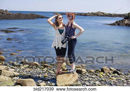 Smiling women standing on rocky beach View Large Photo Image Stock Photo - Smiling women standing on rocky beach. Fotosearch