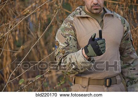 Stock Image - Soldier holding walkie-talkie during training. Fotosearch