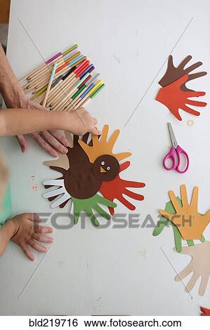 Stock Photograph - Students and teacher making Thanksgiving turkey crafts in classroom. Fotosearch